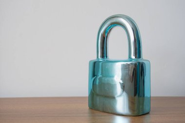 Padlock on brown table, white background. Reflected locked lock with copy space. Privacy protection concept