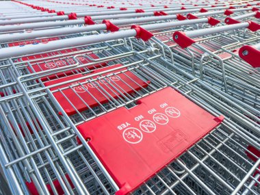 Large group of shopping cart trolley ready for consumers at supermarket. Rows of empty red and silver shopping carts. Retail, organization and consumer concept. Close up