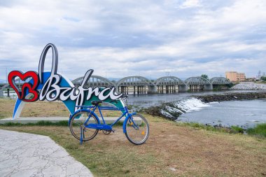 Samsun, Bafra - Turkey - July 2022: River, bridge and bicycle on blue cloudy sky background. Cetinkaya bridge and Kizilirmak river