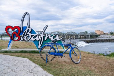 Samsun, Bafra - Turkey - July 2022: River, bridge and bicycle on blue cloudy sky background. Cetinkaya bridge and Kizilirmak river