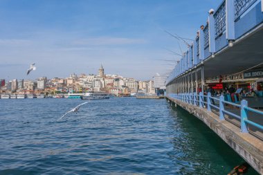 İstanbul, Türkiye - 10 Mart 2023: Galata Kulesi 'nin yer aldığı İstanbul Şehri, Altın Boynuz üzerindeki bir köprüden balıkçılık yapan insanlar