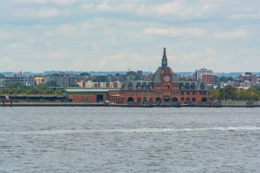 Rıhtımda, üzerinde şehrin ufuk çizgisi olan tarihi bir tuğla bina duruyor. İkonik saat kulesi, nehir kenarındaki manzaraya karakter katıyor.