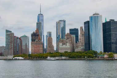 Manhattan gökdelenlerinin canlı görüntüsü rıhtıma yansıyan yüksek gökdelenler. Şehir manzarası, dünyanın en ikonik şehirlerinden birinde şehir hayatının ve modern mimarinin özünü yakalıyor.