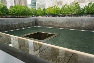 Şehir binaları ve yemyeşil ağaçlarla çevrili sakin bir şelale manzarası hareketli bir şehirde bir yansıma ve hatıra anı yakalıyor..