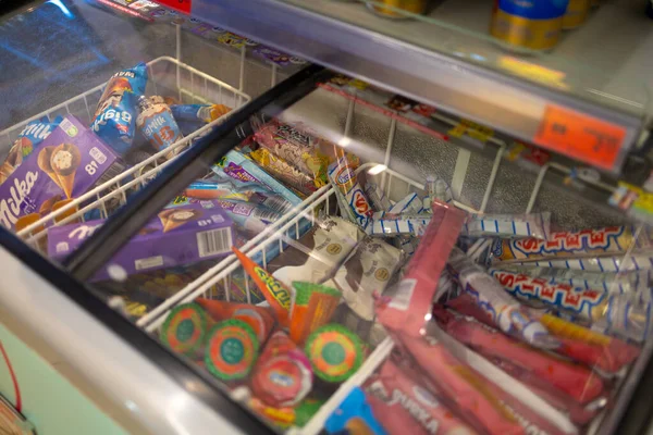 Ekranda çeşitli dondurma ve dondurulmuş yiyeceklerin net bir şekilde görüldüğü görülüyor. Müşteriler çeşitli marka ve tatları görebilir. Sahne, parlak ışıklandırmalı bir mağaza ayarını gösteriyor..