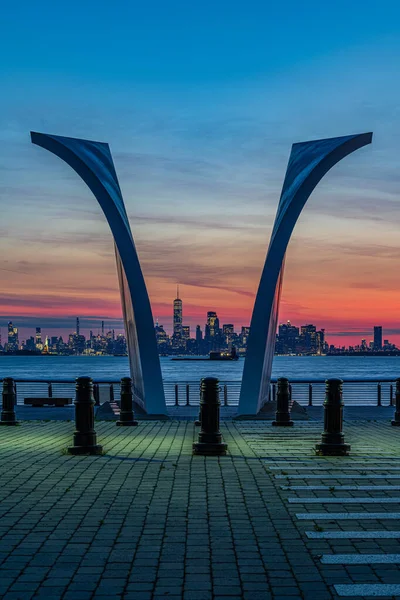 Vue de l'autre côté de Upper Bay et Manhattan depuis Staten Island à travers une paire d'ailes du monument commémoratif du 11 septembre au lever du soleil — Photo