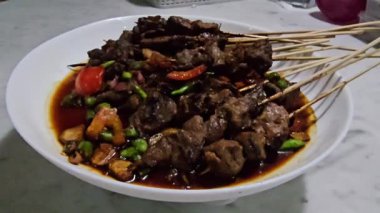 Sate kambing, Keçi eti sate, Keçi satay, koyun eti Endonezya mutfağı soya soslu ızgara keçi eti, dilimlenmiş arpacık soğanı, dilimlenmiş cayyene biberi, doğranmış domates ve salatalık ile servis edilir.