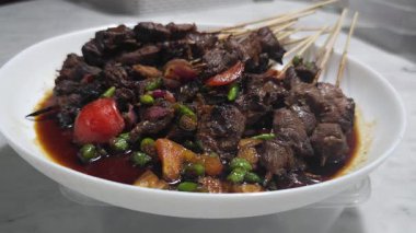 Sate kambing, Keçi eti sate, Keçi satay, koyun eti Endonezya mutfağı soya soslu ızgara keçi eti, dilimlenmiş arpacık soğanı, dilimlenmiş cayyene biberi, doğranmış domates ve salatalık ile servis edilir.