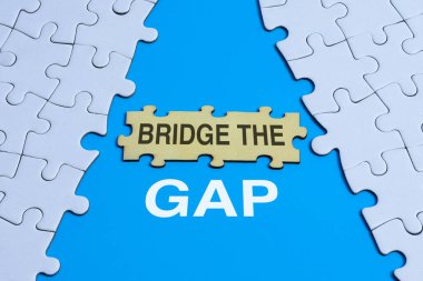 Beyaz ve ahşap yapboz parçaları ile mavi arka plandaki boşluklar, problemler ve çözümler, bağlantı ve ilerleme arasındaki boşluğu doldurma kavramını gösteriyor.