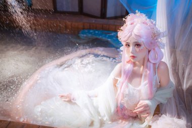 Pembe saçlar ve karmaşık makyajla bezenmiş, huzurlu bir su bahçesinde huzur içinde dinlenen, harikalar ve hayaller uyandıran ruhani bir peri tasviri..