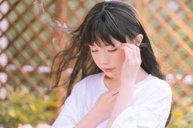 Huzurlu bir güzelliğin görüntüsünü yakalayın. Bu genç bayanın yumuşak altın güneş ışığıyla yıkandığı, saçlarının hafifçe aktığı. Huzuru, yansımayı ve doğal zarafeti iletmek için mükemmel..