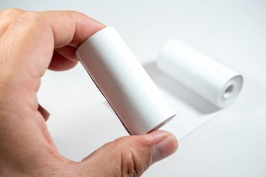 Kağıdın kimyasal tabakasıyla doğrudan teması simgeleyen termal kağıt rulo tutan bir el, BPA (Bisphenol A), bir endokrin parçalayıcı içeriyor olabilir..