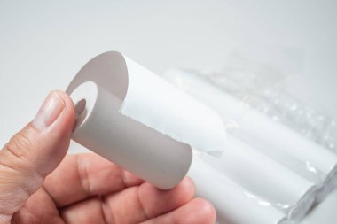 Kağıdın kimyasal tabakasıyla doğrudan teması simgeleyen termal kağıt rulo tutan bir el, BPA (Bisphenol A), bir endokrin parçalayıcı içeriyor olabilir..