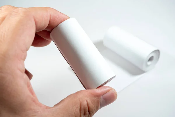 Kağıdın kimyasal tabakasıyla doğrudan teması simgeleyen termal kağıt rulo tutan bir el, BPA (Bisphenol A), bir endokrin parçalayıcı içeriyor olabilir..