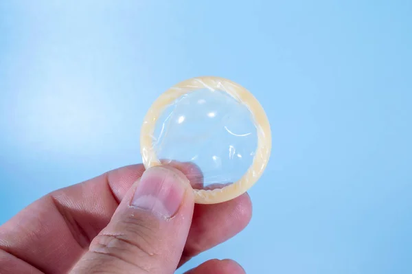 Mavi arka planda sarılmış bir prezervatif resmi. Prezervatif kullanmak bel soğukluğu, klamidya, trikomonez, hepatit B ve HIV riskini önemli ölçüde azaltır..