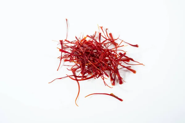 Temiz beyaz arka planda izole edilmiş küçük, canlı bir kırmızı safran iplik yığını (stigma).