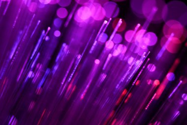 Zifiri karanlıkta parlayan parlak morumsu ve mor fiber optik iplikçiklerin canlı, soyut bir yakın çekimi..