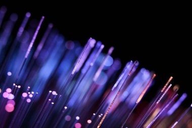 Zifiri karanlıkta parlayan parlak morumsu ve mor fiber optik iplikçiklerin canlı, soyut bir yakın çekimi..