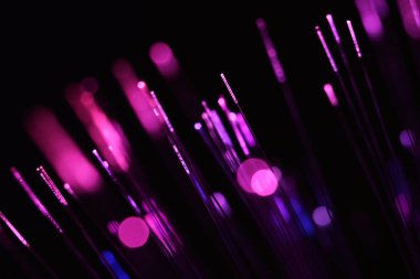Zifiri karanlıkta parlayan parlak morumsu ve mor fiber optik iplikçiklerin canlı, soyut bir yakın çekimi..