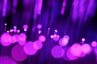 Zifiri karanlıkta parlayan parlak morumsu ve mor fiber optik iplikçiklerin canlı, soyut bir yakın çekimi..