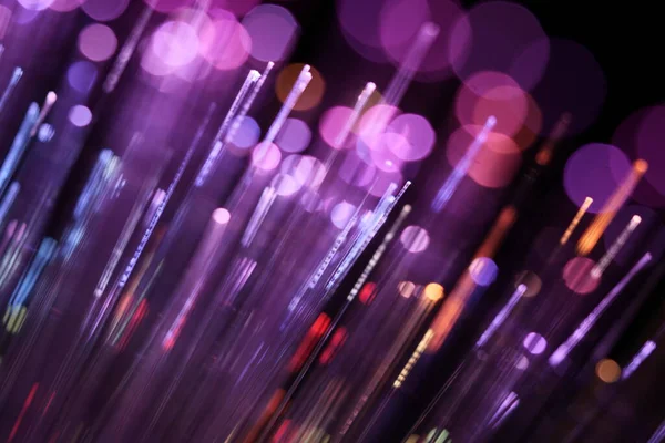Zifiri karanlıkta parlayan parlak morumsu ve mor fiber optik iplikçiklerin canlı, soyut bir yakın çekimi..