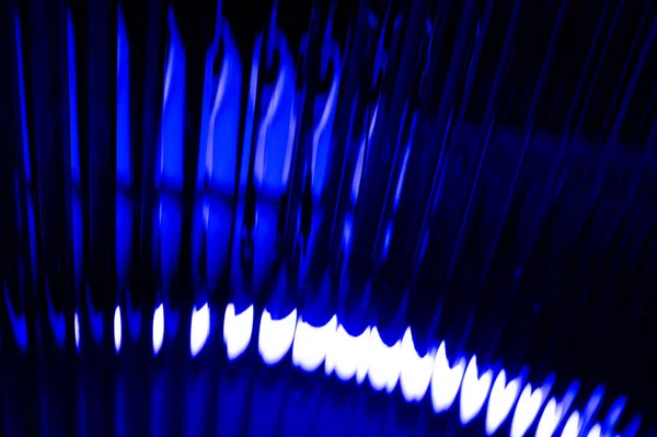 Dalgalanan koyu soyut arkaplan, yoğun mavi ışık yansımaları ve gölgeler, dinamik bir doku yaratıyor..