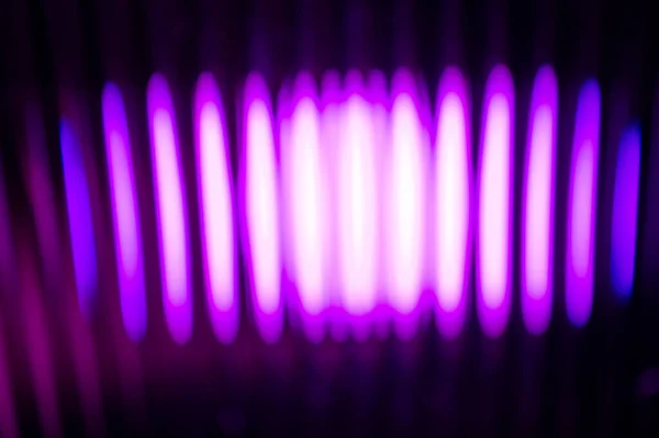 Soyut, canlı bir mor ışık kaynağı karanlık ve gizemli bir arkaplanda dikey, ritmik çizgiler oluşturuyor..