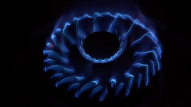 Genellikle kırmızı noktalı, dairesel bir gaz ocağı alevi koyu bir arkaplana yakın planda yakalanır.