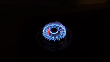 Genellikle kırmızı noktalı, dairesel bir gaz ocağı alevi koyu bir arkaplana yakın planda yakalanır.