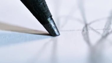 Kalem ucunu hareket halinde gösteren, grafit ve kağıdın dokusunu vurgulayan, yoğun bir odaklanma ve yaratıcı bir sürecin başladığını gösteren aşırı makro bir çekim.