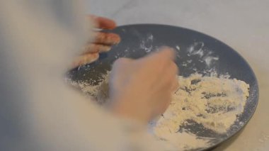 Bir kadın yemek pişirmeden önce un tozlu bir şurubu tabakta şekillendirir ve düzleştirir. Ev mutfağında geleneksel bir Slav süzme peynirli krep..