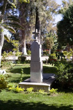 Mezarlıkta bahçenin ortasında haç olan büyük bir mezar taşı.