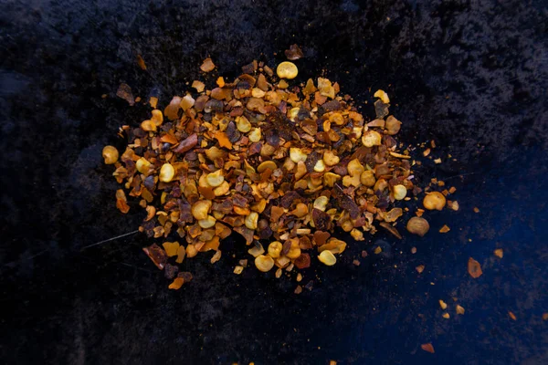 Siyah bir tava yüzeyinde kuru biber taneleri yığını, yakın ve üst görünüm