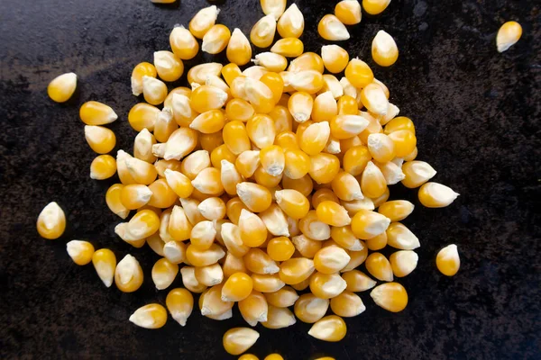 Patlamış mısır çekirdekleri siyah bir tava yüzeyinde daire şeklinde dizilmiş.