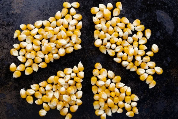 Sarı mısır taneleri siyah bir tava yüzeyinde barış sembolü olarak dizilmiş.