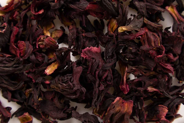 Kurumuş Hibiscus Sabdariffa (Jamaika çiçeği) beyaz bir yüzeye yaklaşır 