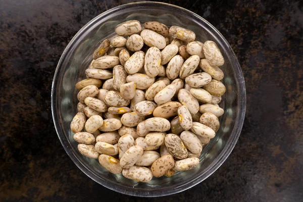 Siyah bir tava yüzeyindeki cam bir kabın içindeki Pinto fasulyesi