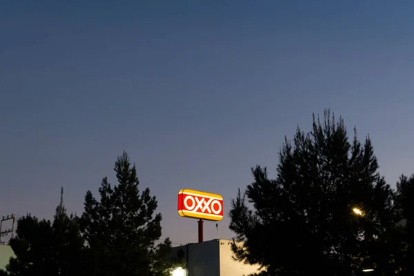 Ramos Arizpe, Coahuila, Meksika - 22 Ocak 2025 - Çam ağaçları arasında alacakaranlık gökyüzü ile Oxxo işareti