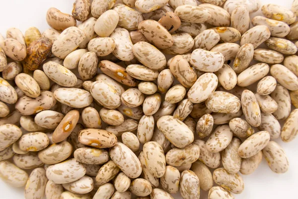 Pinto fasulyeleri beyaz bir yüzeye saçılmış.