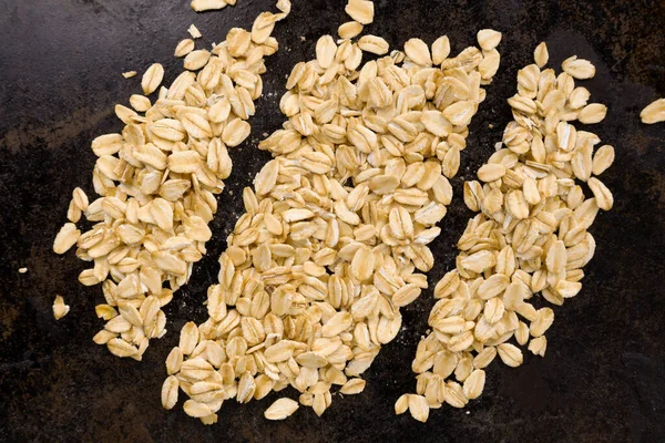 3 parçaya bölünmüş bir yığın yulaf ezmesi, siyah tava desenli bir arka plan üzerine