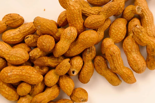 Beyaz bir yüzeyde kabuklu bir avuç fıstık.