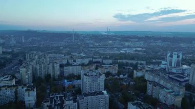 Chisinau 'nun mavi saatte havadan manzarası. İnsansız hava aracı apartmanların ve iş kulelerinin üzerinde, yumuşak akşam ışığında trafiğin üzerinde ve ufuk çizgisinde yavaşça ilerliyor. Modern şehir havası, ticari kullanım için temiz. 