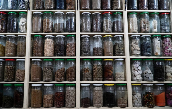 Glass jars filled with dried spices, herbs, and grains arranged on wooden shelves. Perfect for the pantry, kitchen, and your culinary creations.