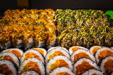 Taze balık, pirinç ve yosun da dahil olmak üzere suşi rulolarının lezzetli bir fotoğrafı bir tabakta servis ediliyor. Canlı renklerle güzel bir sunum, yemek, aşçılık ve restoran temaları için mükemmel..