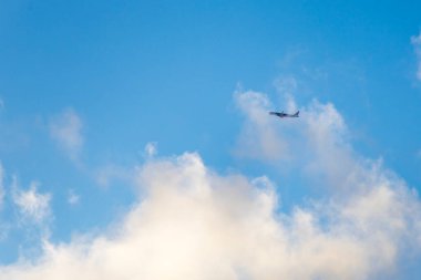 Mavi gökyüzünde bulutlarla uçan bir uçağın güzel fotoğrafı. Seyahat, özgürlük, havacılık ve macera sembolü - ulaşım, turizm ve iş temaları için mükemmel.