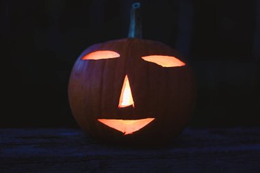 Karanlıkta parlayan oyulmuş balkabaklarıyla ürkütücü Cadılar Bayramı fotoğrafı. Mum ışığı, turuncu balkabakları ve mevsimlik süslemeleri olan şenlikli sonbahar atmosferi. Bayram, Cadılar Bayramı ve sonbahar temaları için mükemmel..