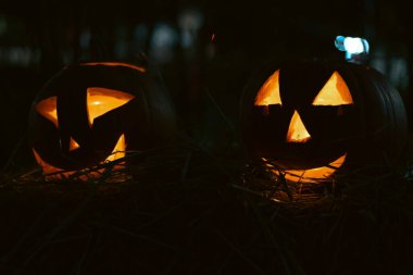 Karanlıkta parlayan oyulmuş balkabaklarıyla ürkütücü Cadılar Bayramı fotoğrafı. Mum ışığı, turuncu balkabakları ve mevsimlik süslemeleri olan şenlikli sonbahar atmosferi. Bayram, Cadılar Bayramı ve sonbahar temaları için mükemmel..