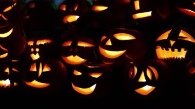 Cadılar Bayramı. Işıl ışıl Cadılar Bayramı balkabakları (kriko-fenerler) gecenin karanlığında içinde titreyen mumlar, ürkütücü ve şenlikli sonbahar atmosferi, 4K ultra HD görüntü.