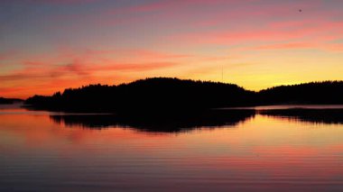 Güzel sonbahar gündoğumu deniz üzerinde altın güneş ışığı, yumuşak sis su ve orman kıyı şeridi üzerinde sürükleniyor, 4K ultra HD huzurlu doğa manzarası