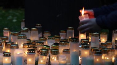 Sessiz bir mezarlıkta mumları yakmak, titreyen sıcak alevler mezar taşlarını yakmak ve 4K ultra HD ile yakalanan barışçıl bir anıt atmosferi yaratmak..